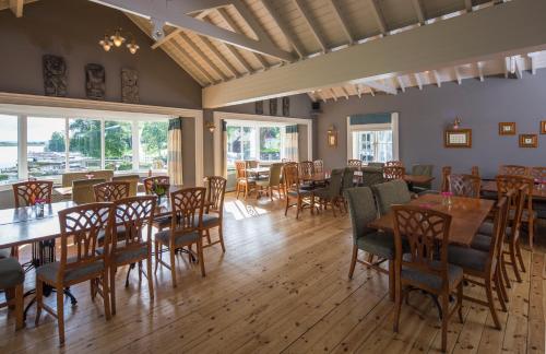 a dining room with tables and chairs and windows at Lusty Beg Island in Kesh
