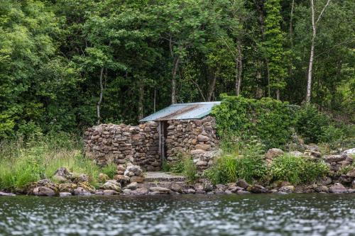 a stone building with a tin roof next to a river at Lusty Beg Island in Kesh