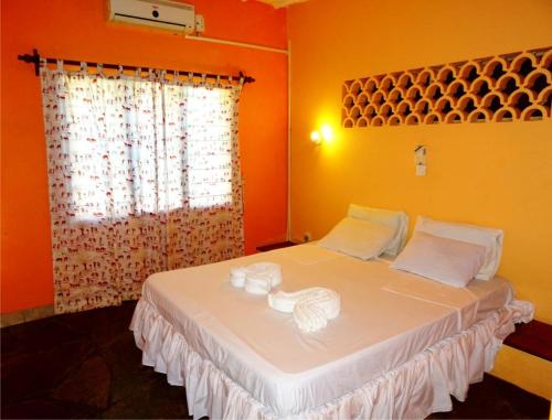 um quarto com uma grande cama branca com paredes cor-de-laranja em Doric Cottages Diani em Diani Beach