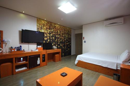 a hotel room with a bed and a flat screen tv at Hotel Lie in Geoje 