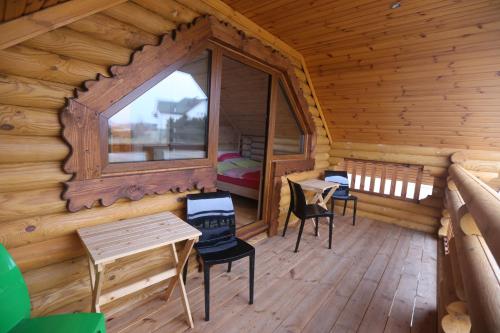 a log cabin with a window and two chairs and a table at Sosnowe Domki in Rewal