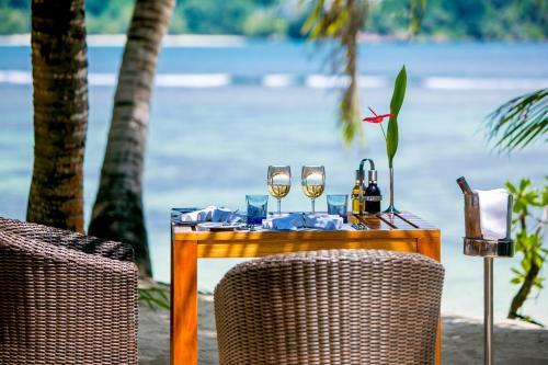 a table with two glasses of wine on it at Kempinski Seychelles Resort in Baie Lazare Mahé