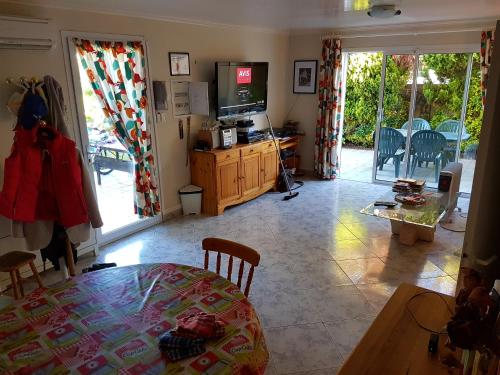 - un salon avec une télévision et une table à manger dans l'établissement MAISON Bernardo NATURIST, au Cap d'Agde