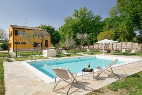 a swimming pool with two chairs and a house at Montenovo Country House in Ostra Vetere