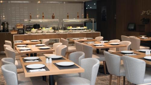 イスタンブールにあるYuksel Istanbul Yenikapı Hotelの木製のテーブルと椅子が備わるレストラン、ビュッフェ式料理