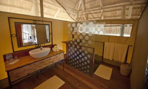 uma casa de banho com um lavatório e um espelho em Mbali Mbali Tarangire River Camp em Kwa Kuchinia