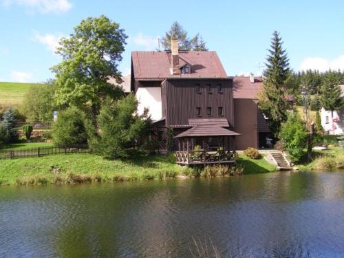 a house sitting on the side of a lake at Chata Barborka in Loučná pod Klínovcem