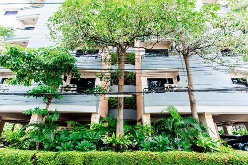 an apartment building with trees in front of it at Grand Residence Ngamwongwan 19 in Nonthaburi