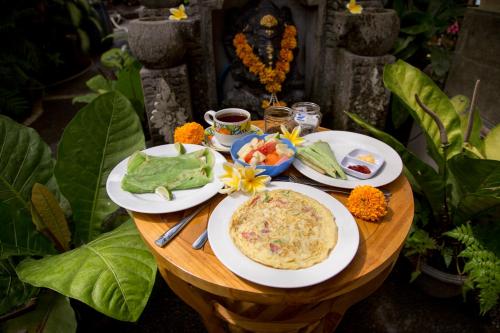 ウブドにあるCIK'S ゲストハウスの食べ物の皿が置かれた木製のテーブル