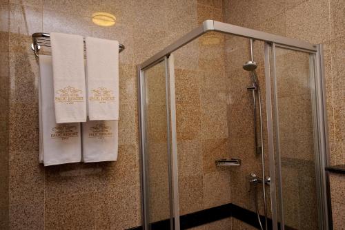 a bathroom with a shower with white towels at Hotel & Spa PALIĆ RESORT in Palić