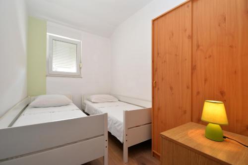 a bedroom with two beds and a desk with a lamp at Apartmani Šime in Betina