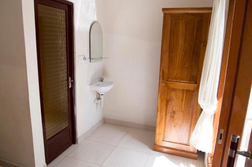 uma casa de banho com um lavatório e uma porta de madeira em CIK'S Guest House em Ubud