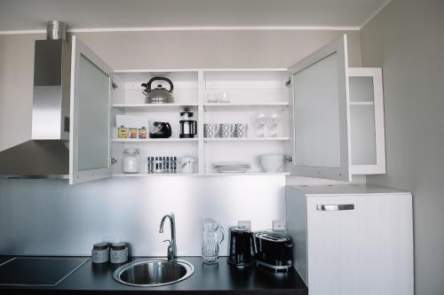 a kitchen with white cabinets and a sink at Hestia Apartments Seaport in Tallinn