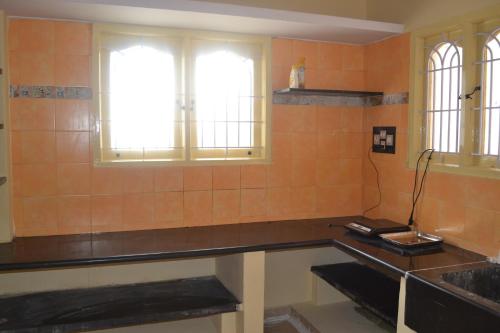 eine Küche mit einer Theke, einem Waschbecken und Fenstern in der Unterkunft Manasvini Homestay-A home in Mysore with scenic view in Mysore