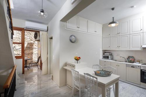 a kitchen with white cabinets and a table and chairs at Loggia Ηome in Rethymno Town