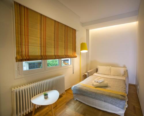 アテネにあるSkoufa Apartmentのベッドルーム1室(ベッド1台、テーブル、窓付)