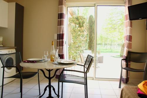 comedor con mesa, sillas y ventana en Résidence Les Peupliers, en Loriol-du-Comtat