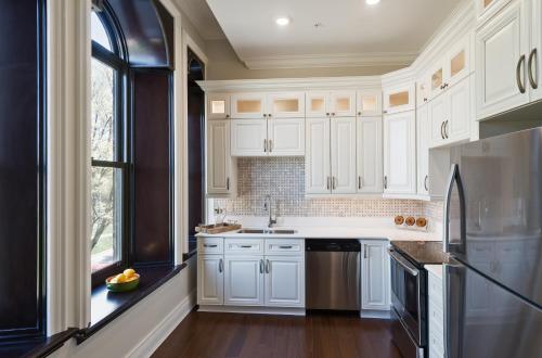 a kitchen with white cabinets and a window at Sydney Boutique Inn & Suites in Charlottetown