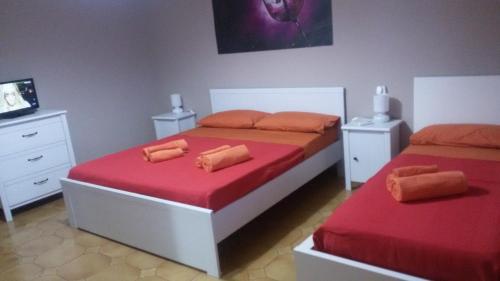 ナルドにあるMalvasia casa vacanzeのベッドルーム1室(赤いシーツとベッド2台、テレビ付)