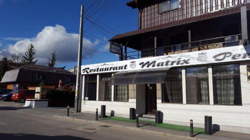 a white building with a sign on the side of it at Pensiune Matrix in Curtea de Argeş