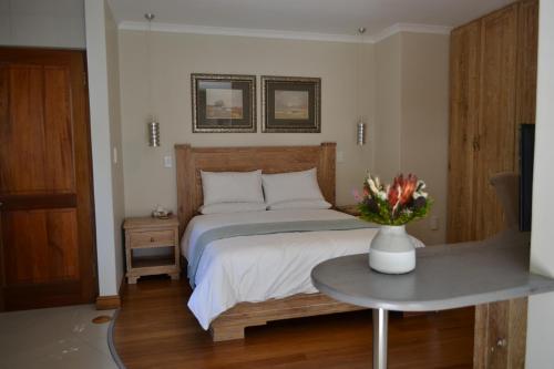 a bedroom with a bed and a table with a vase of flowers at Lydall Wild Tranquil Garden Suites in Johannesburg
