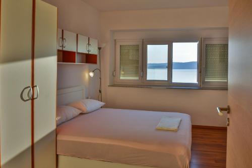 Un dormitorio pequeño con una cama y dos ventanas. en Apartment Petra, en Senj