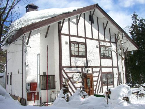 a white house with snow on the side of it at Gallery & Lodge Noichigo in Hakuba
