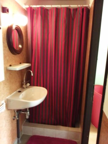 a bathroom with a red shower curtain and a sink at Magdaléna Vendégház in Bük