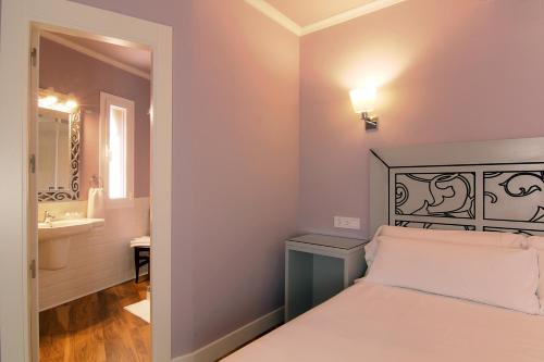 a bedroom with a bed and a bathroom with a sink at Hostal Los Castañuelos in Candeleda
