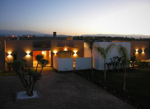 a house with lights and palm trees at night at Villa Jardins D'Isa in Marrakech