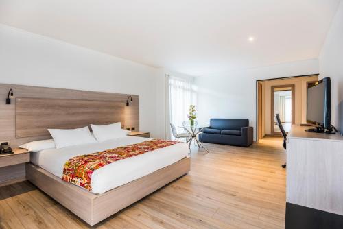 una camera con un grande letto e una televisione di Hotel Rosales Plaza a Bogotá