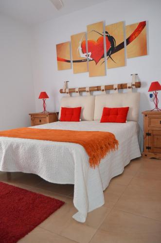 a bedroom with a large white bed with red pillows at Residencial Jandía Marina in Morro del Jable