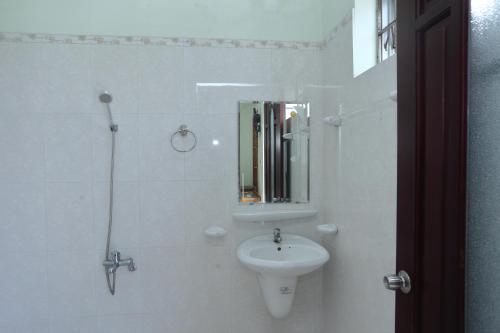 a white bathroom with a sink and a mirror at Sea View Villa in Long Hai