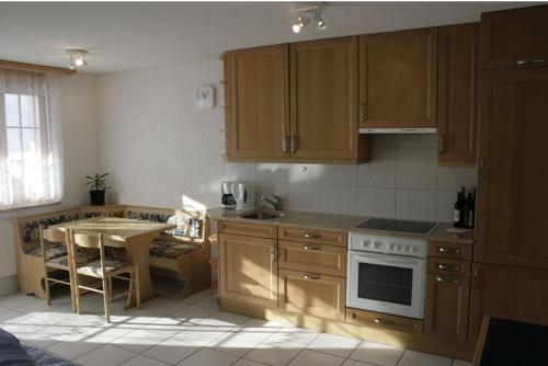 uma cozinha com armários de madeira, uma mesa e um fogão em Residence Selika em Leuk