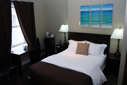a bedroom with a large white bed with two windows at The Duckworth Inn in St. John's