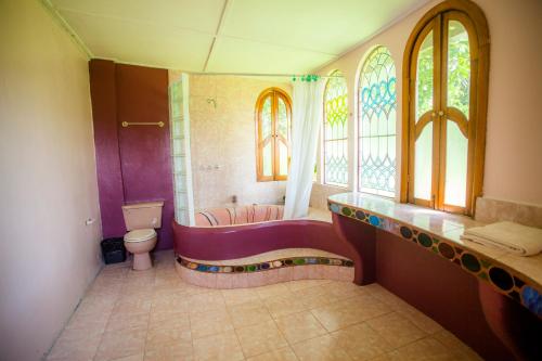 a bathroom with a tub and a toilet and windows at Banana Bank Lodge & Jungle Horseback Adventures in Belmopan