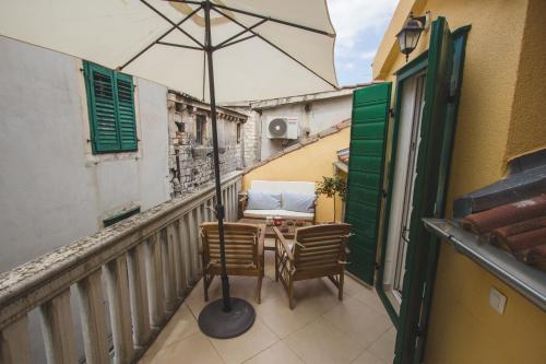 a balcony with a table and chairs and an umbrella at Jerry & Oli's Apartments in Šibenik
