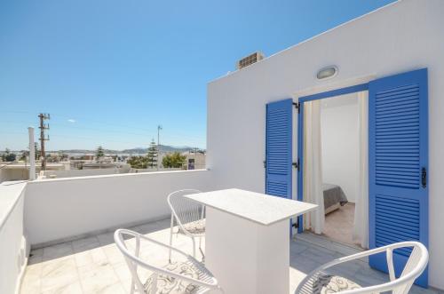 a balcony with a table and chairs and a blue door at Windmill Naxos in Naxos Chora