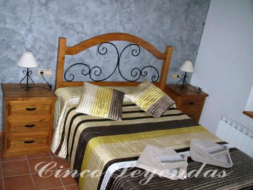a bedroom with a wooden bed with two dressers and two lamps at Cinco Leyendas in Liegos