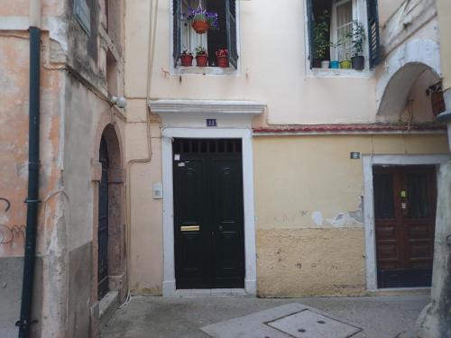 a building with a black door and two windows at Casa del Centro Storico in Corfu Town