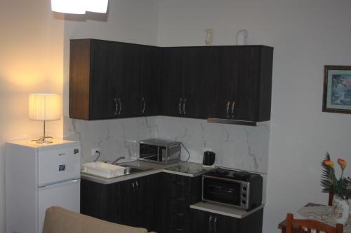 a small kitchen with a microwave and a refrigerator at Relax Apts Saranda in Sarandë