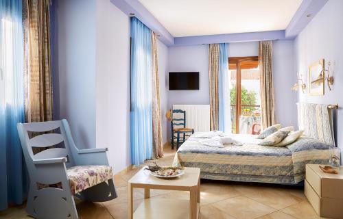 Schlafzimmer mit blauen Wänden, einem Bett und einem Stuhl in der Unterkunft Archodiko Toliadi Boutique Apartments and Suites in Ouranoupoli