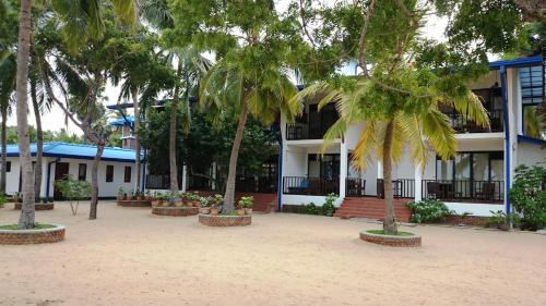a building with palm trees in front of it at Wellé Wadiya Beach Villa in Kalpitiya