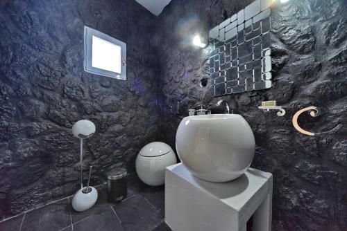 a bathroom with a white toilet in a black wall at AMO Folegandros in Karavostasi