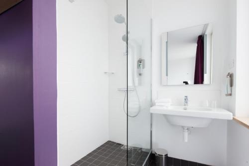 La salle de bains blanche est pourvue d'un lavabo et d'une douche. dans l'établissement ibis Styles Calais Centre, à Calais