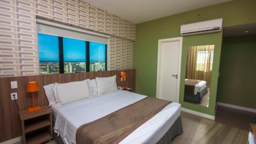 um quarto com uma cama grande e uma janela grande em Mais Hotel Aeroporto Salvador em Lauro de Freitas