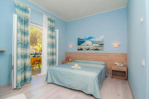 a blue bedroom with a bed and a window at Hotel Marelba in Cavo