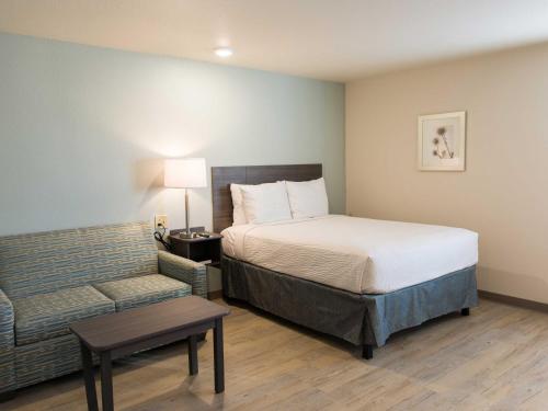 a hotel room with a bed and a couch at WoodSpring Suites Broken Arrow in Tulsa