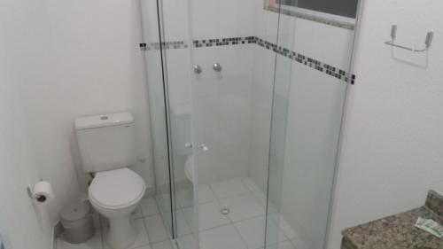 une salle de bain avec toilettes et douche en verre dans l'établissement Pousada Peruíbe Ametista, à Peruíbe
