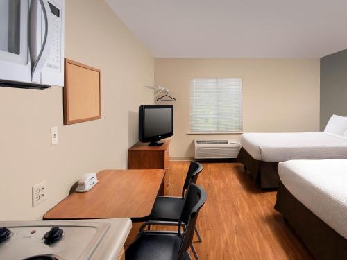 a small hotel room with a desk and a bed and a television at WoodSpring Suites Council Bluffs in Council Bluffs